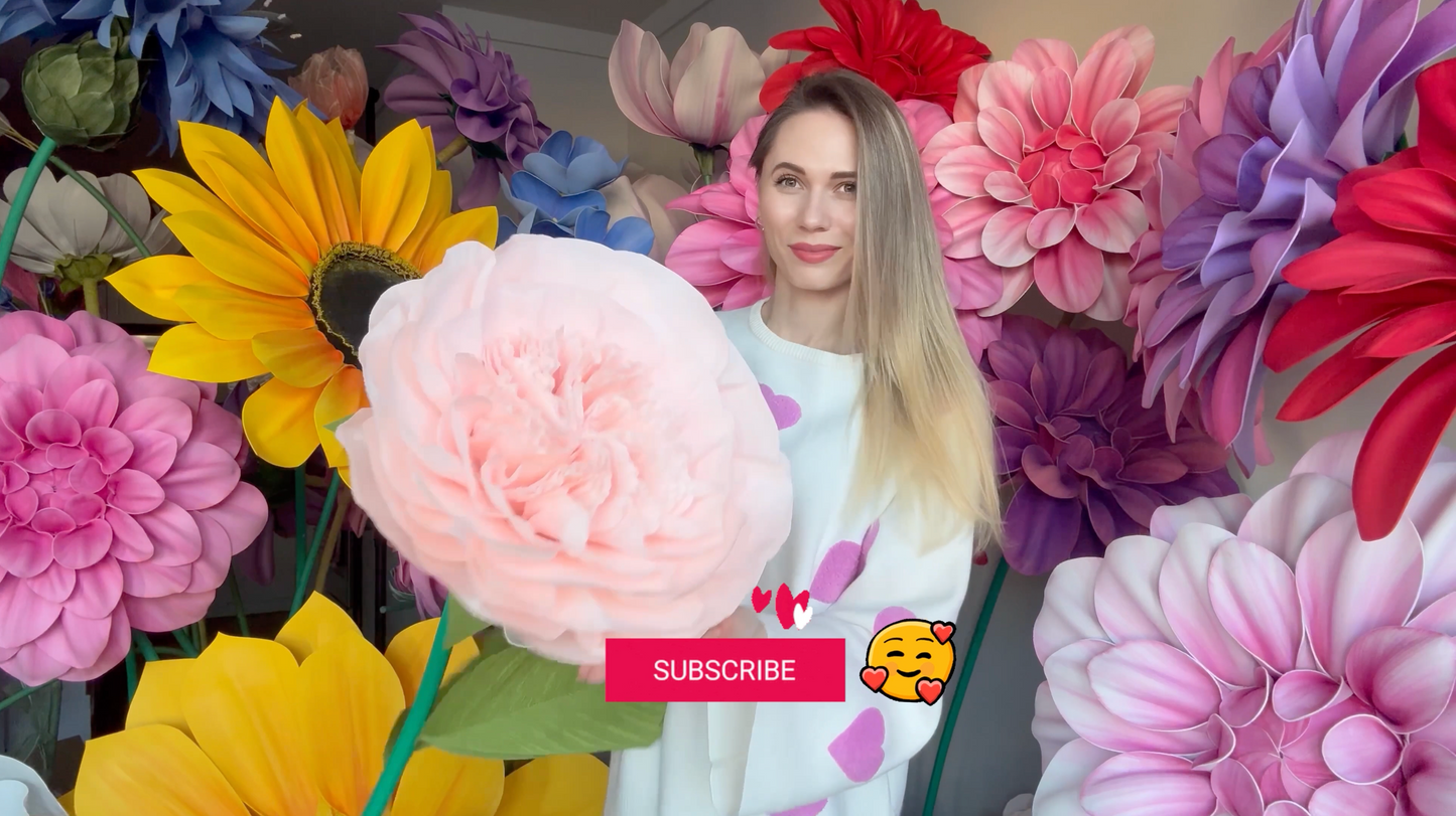 Alina Blossom standing among Giant flowers with a 'Subscribe' YouTube button overlay.