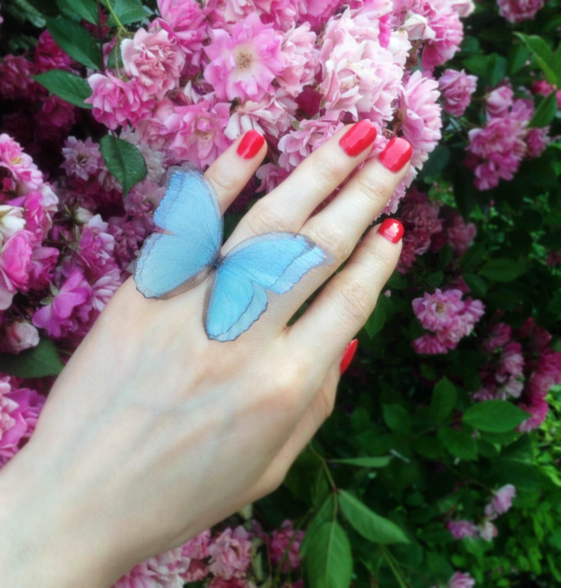 Blue butterfly ring on finger for size comparison