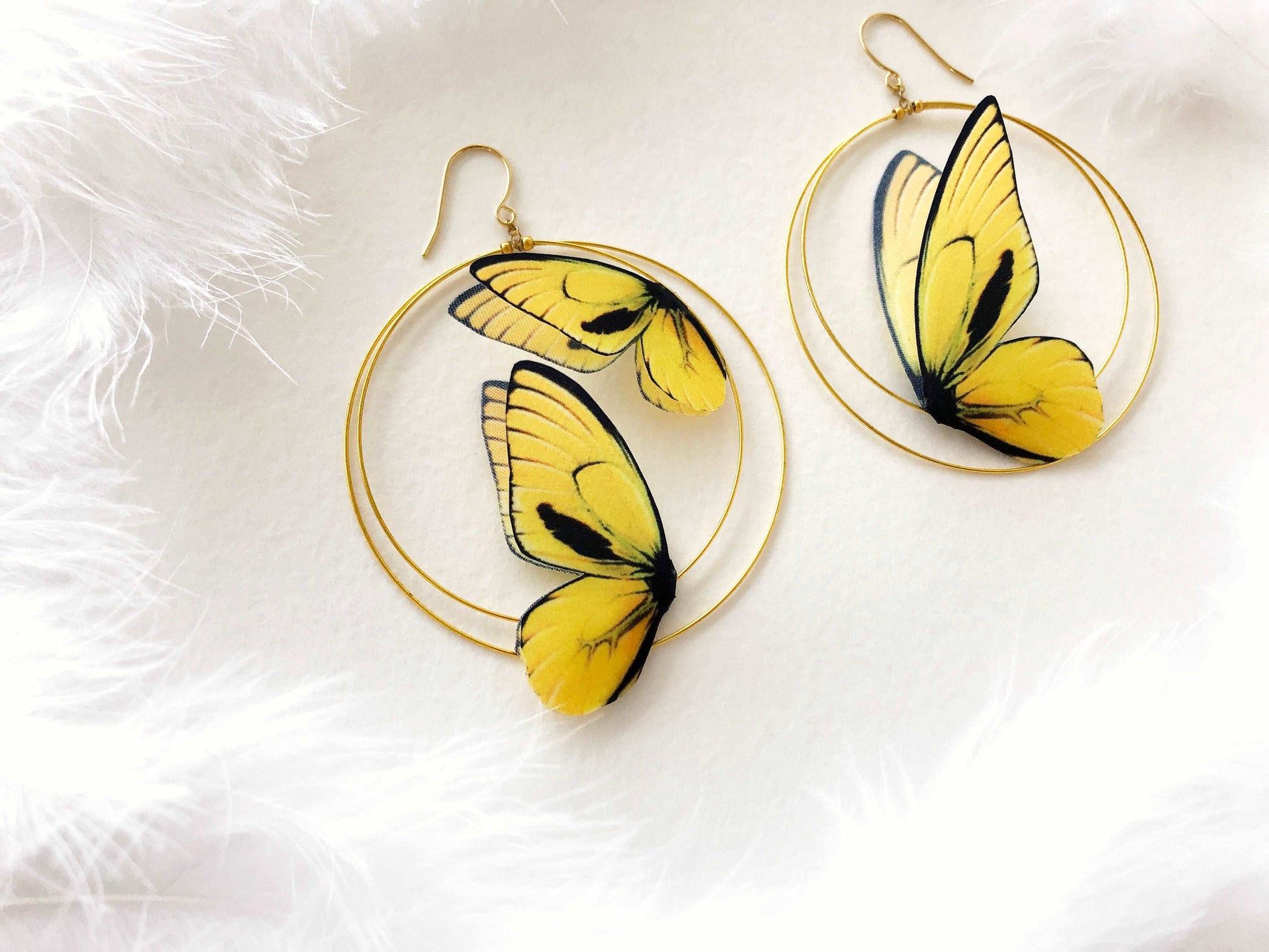 Double Hoop Earrings with Faux Butterflies in Yellow Color on White Background and Feathers