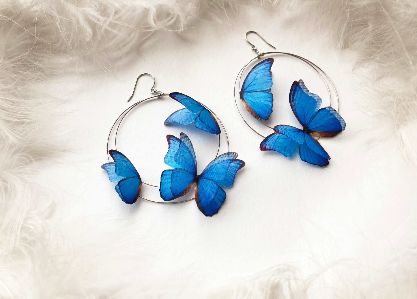 Silver Hoop Earrings with Boho Butterflies on White Feathers Background