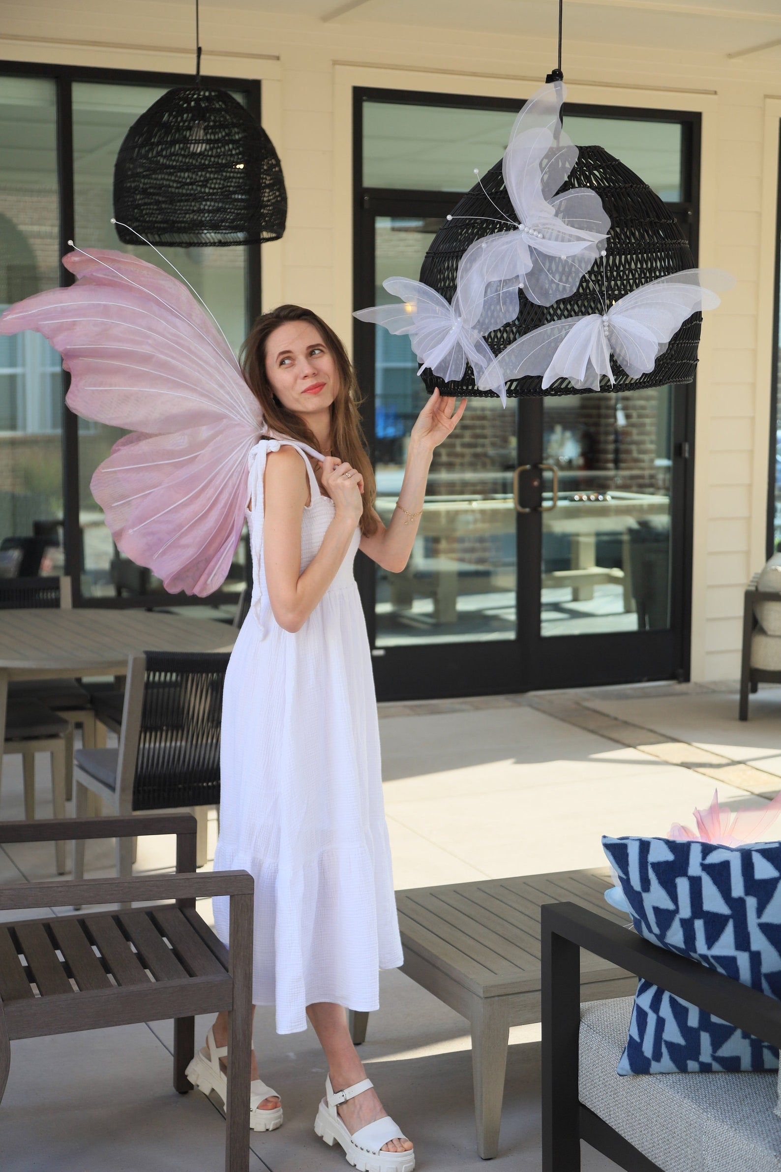 Woman holding pink butterfly wings in an outdoor setting