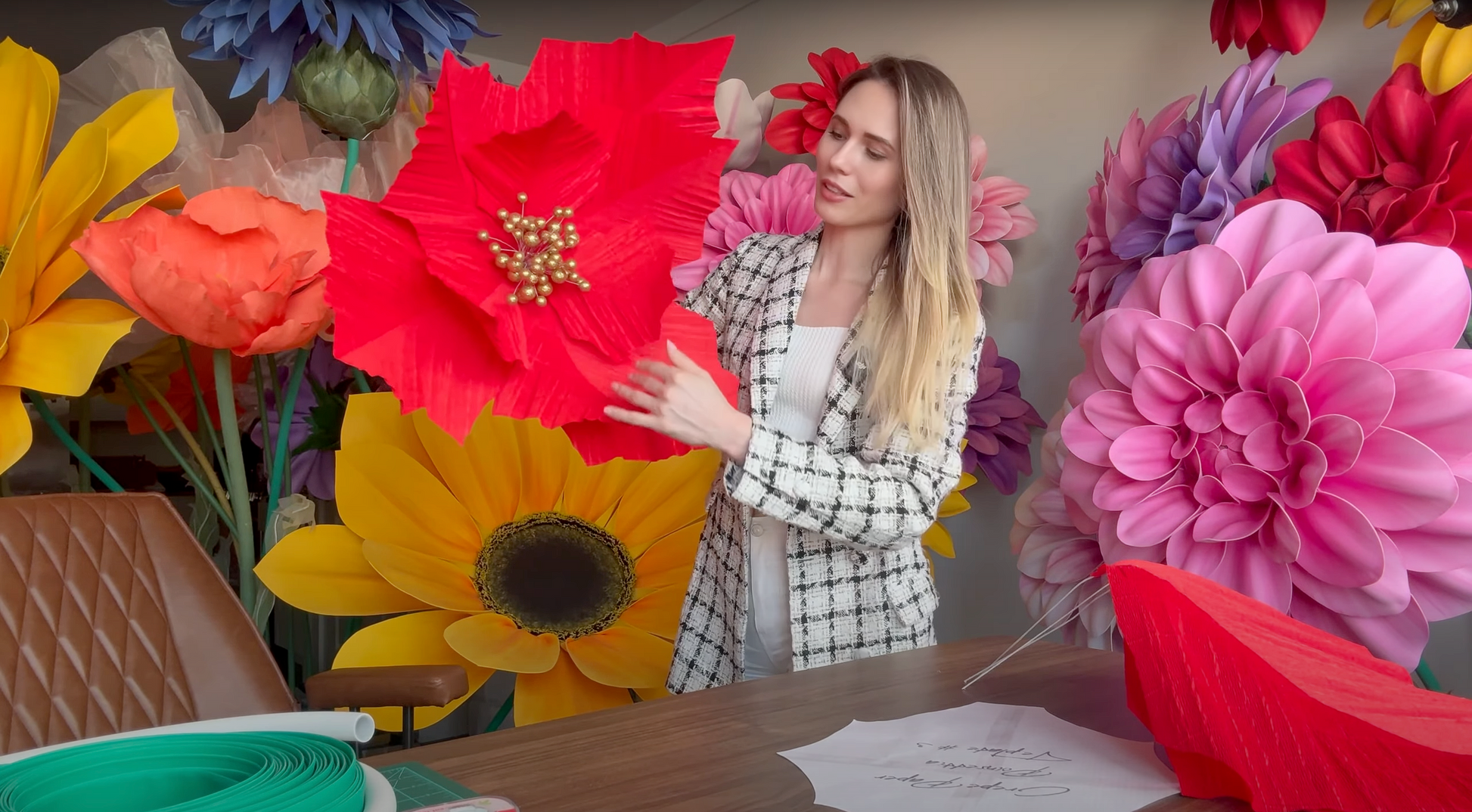 Alina Blossom arranging giant artificial flowers in a decorative setting
