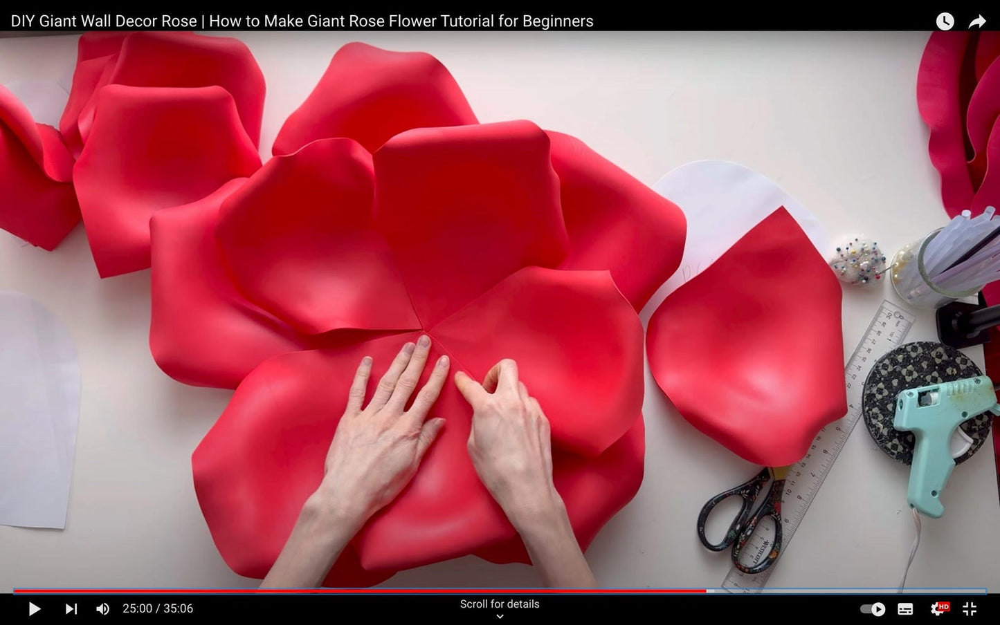 Alina Blossom assembling a large red rose flower with tools on a table.