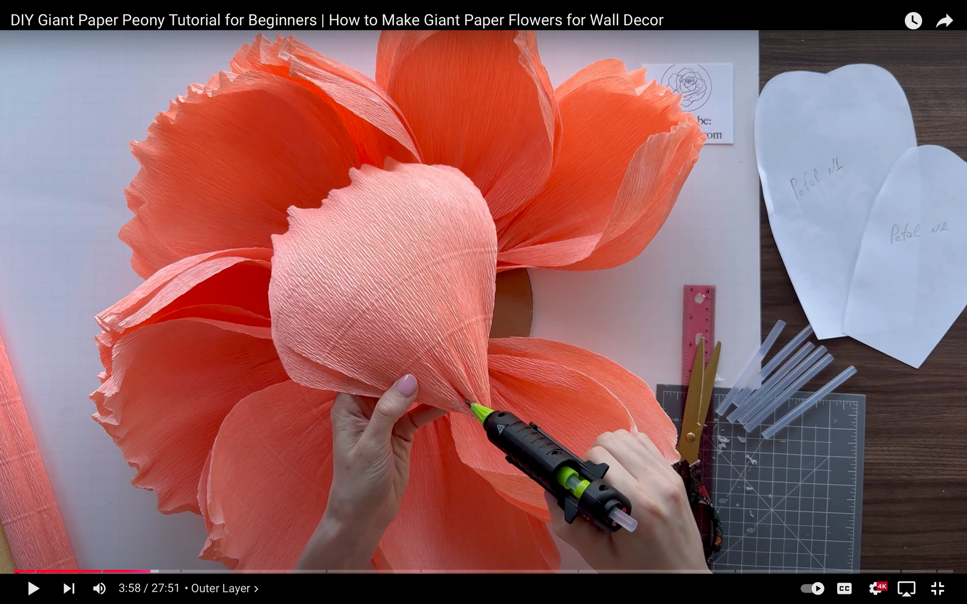 DIY Giant Paper Peony Tutorial for Beginners with hands working on a large coral paper flower.