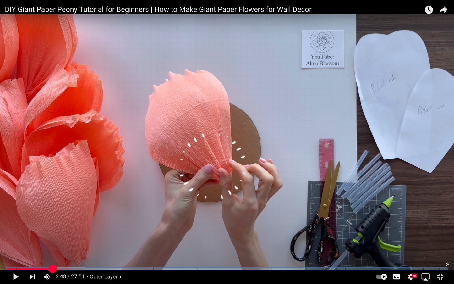 DIY Giant Paper Peony Tutorial for Beginners with hands making a coral paper flower on a white background.