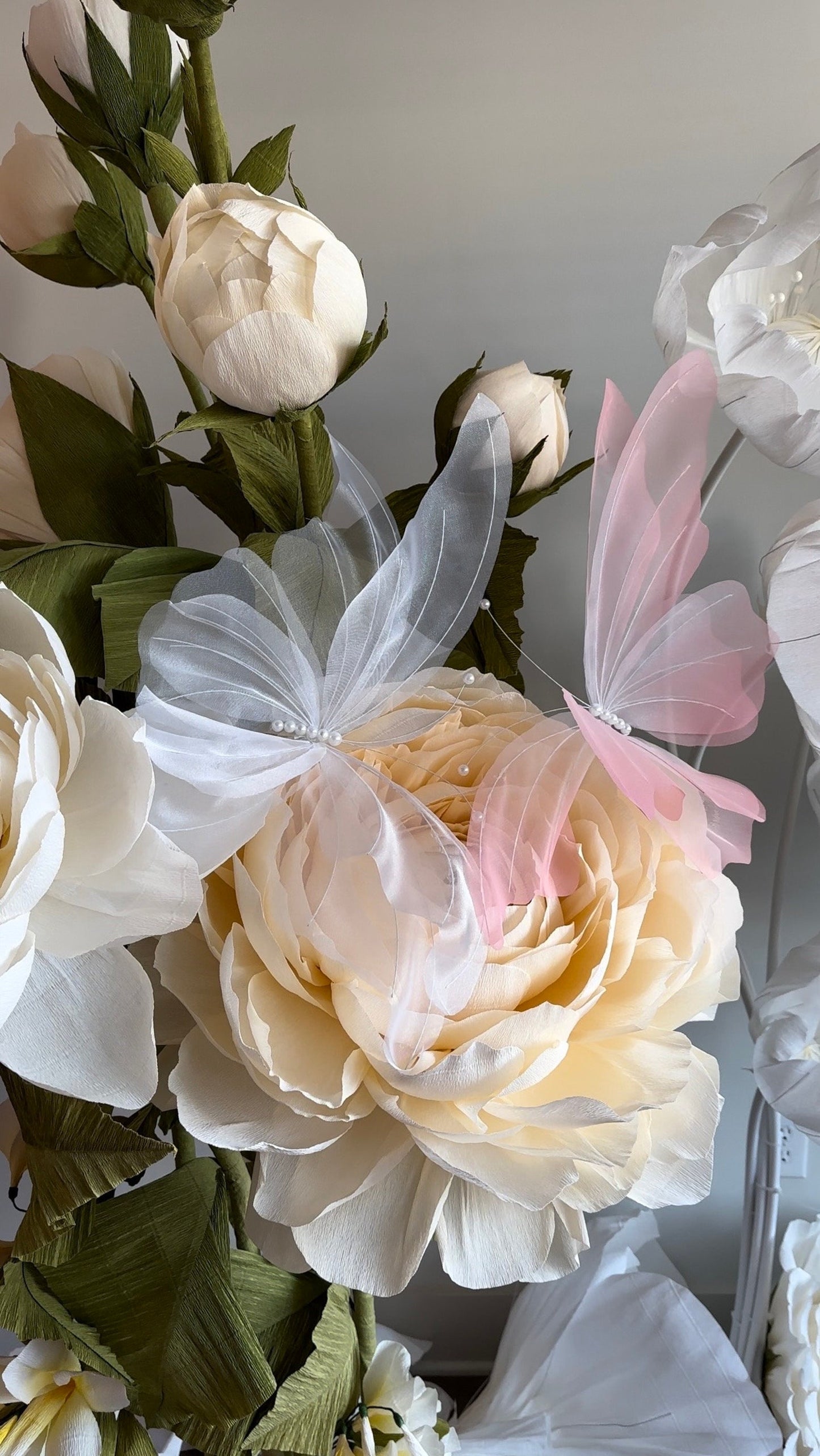 Bouquet of flowers with white, pink, and green elements on a neutral background