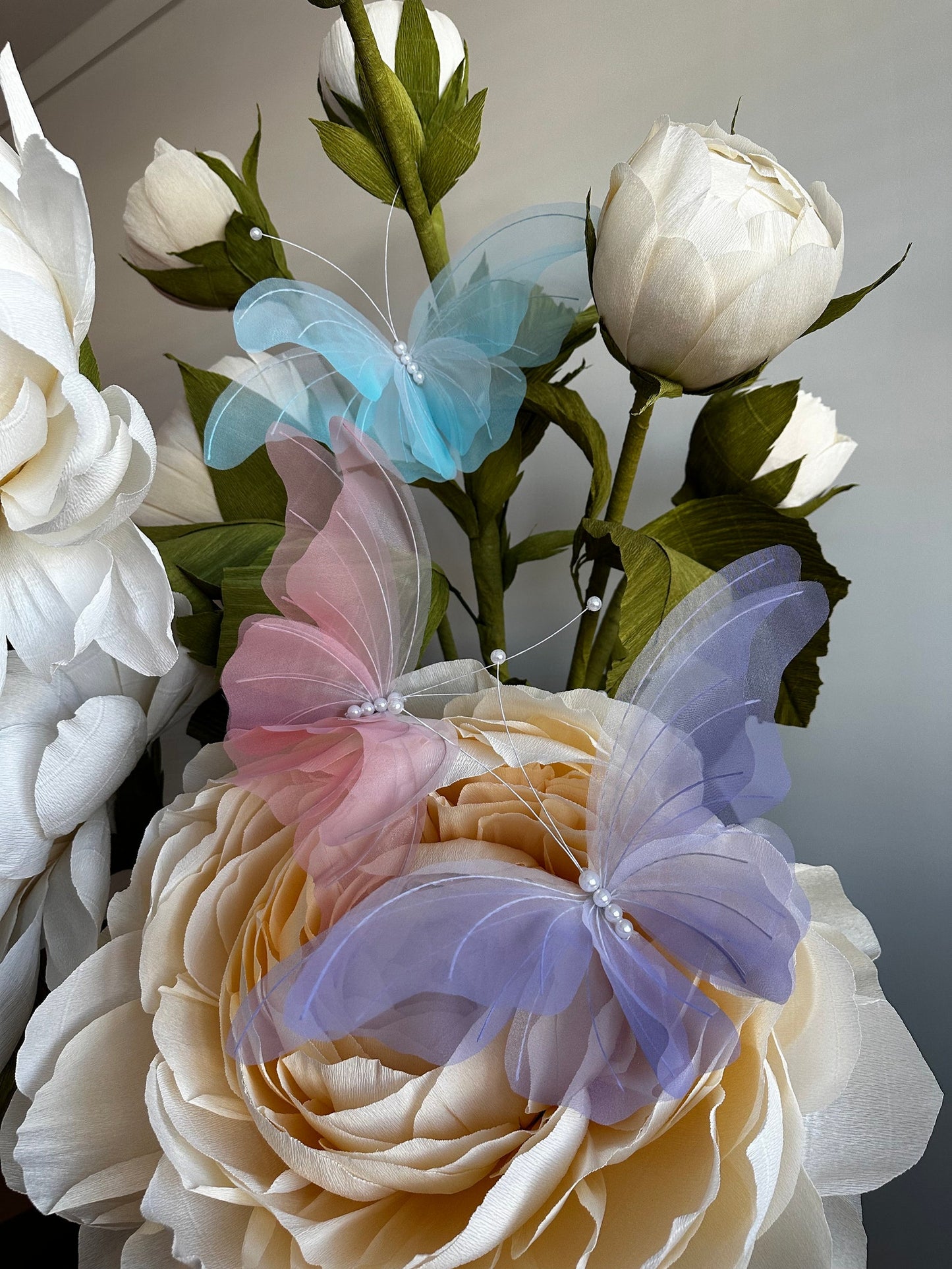 Artificial flowers with butterfly accents on a neutral background
