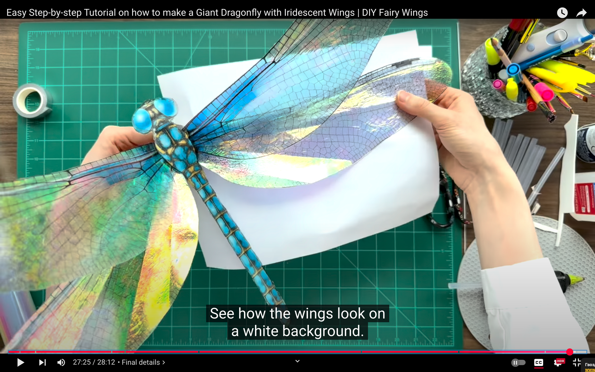 Step-by-step tutorial on making a giant dragonfly with iridescent wings on a cutting mat.