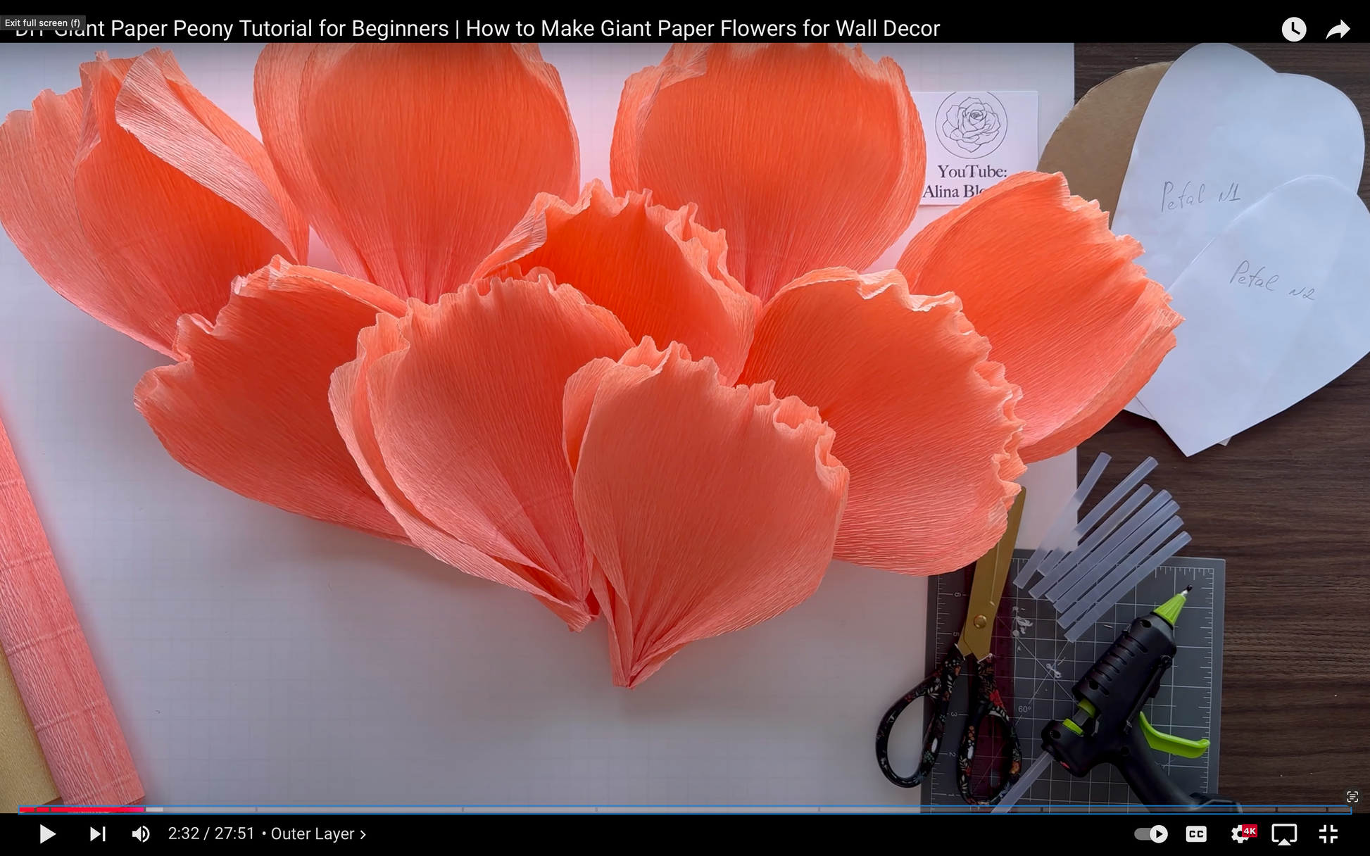 Giant paper peony flowers on a table with crafting tools.