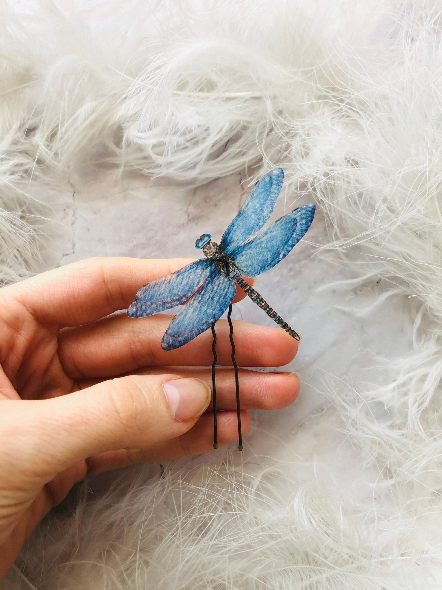 Boho chic dragonfly hair clip with blue silk wings, shown on a hand for size reference