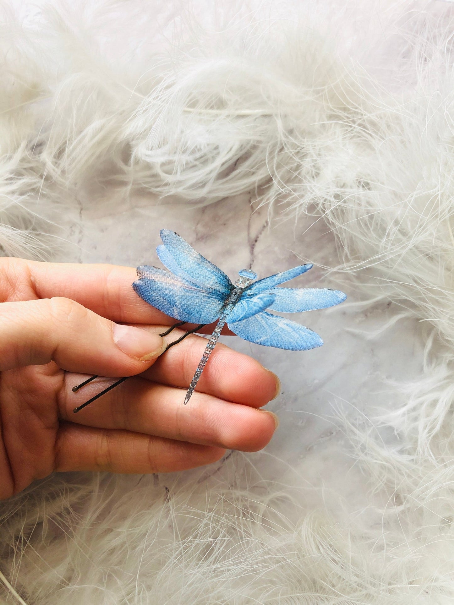 Handcrafted blue dragonfly hairpin made from natural silk, displayed on a hand