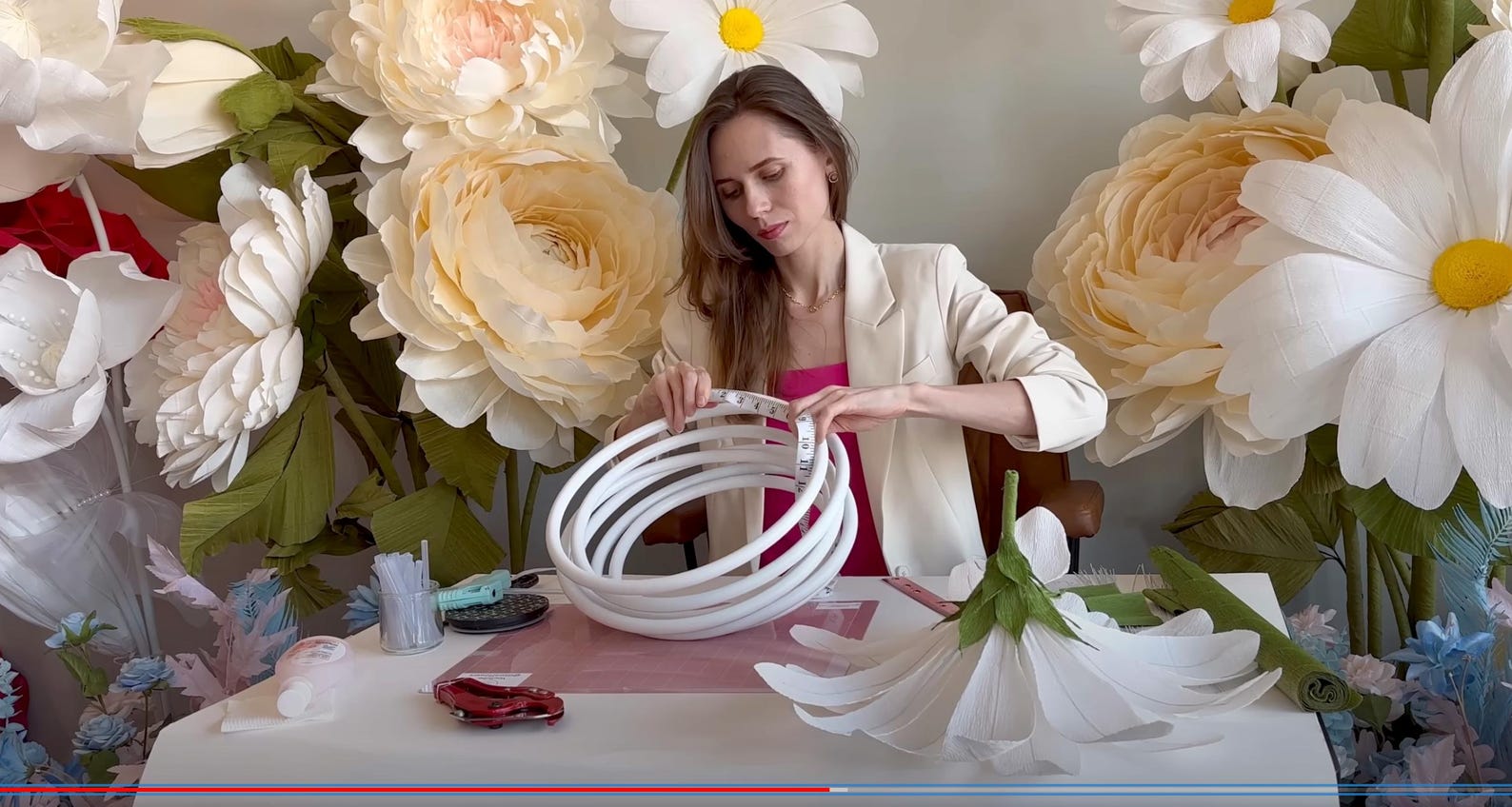 Woman arranging large paper flowers in a decorative setting