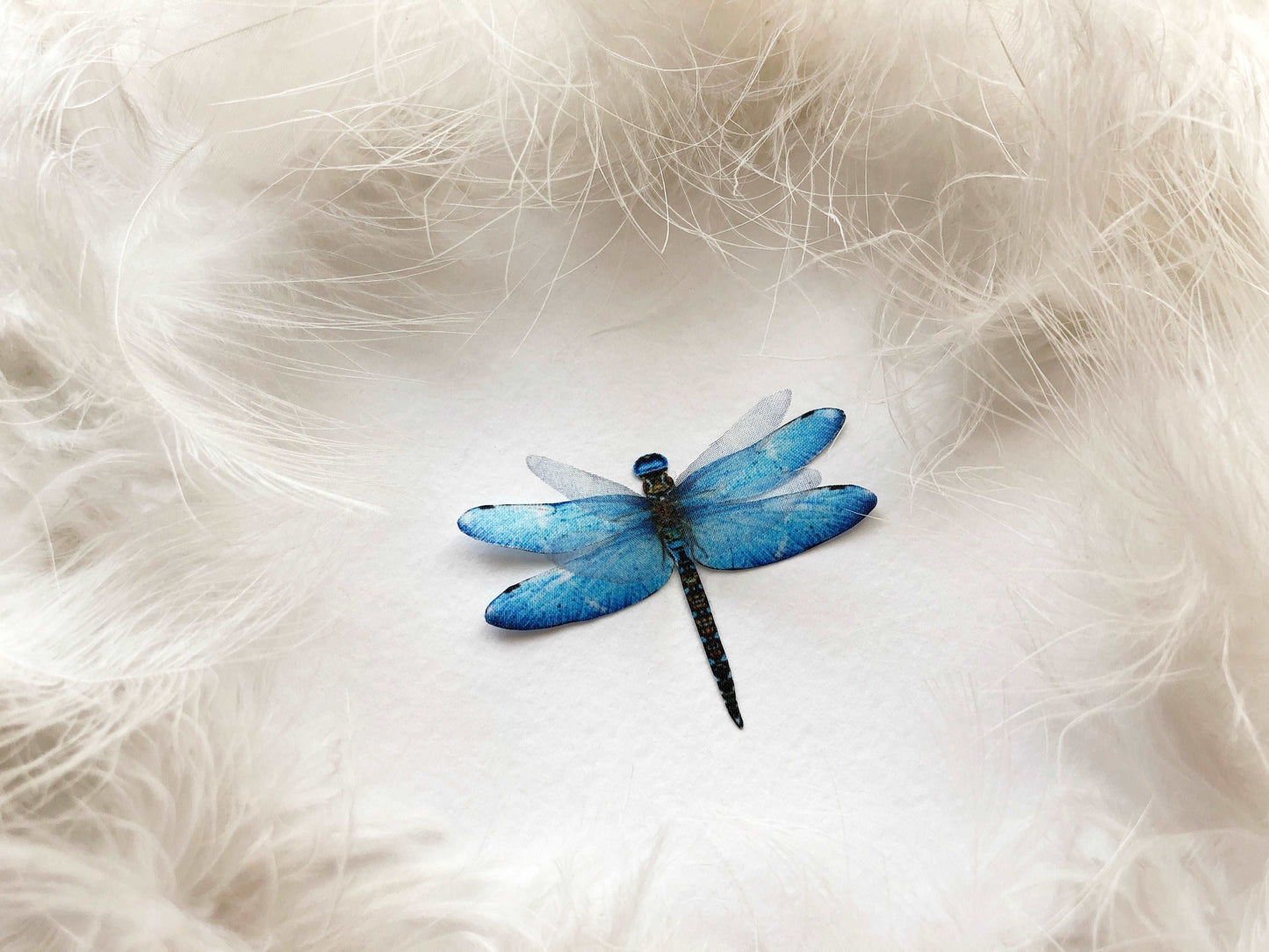 Blue Dragonfly Handmade of Silk on White Feathers Background