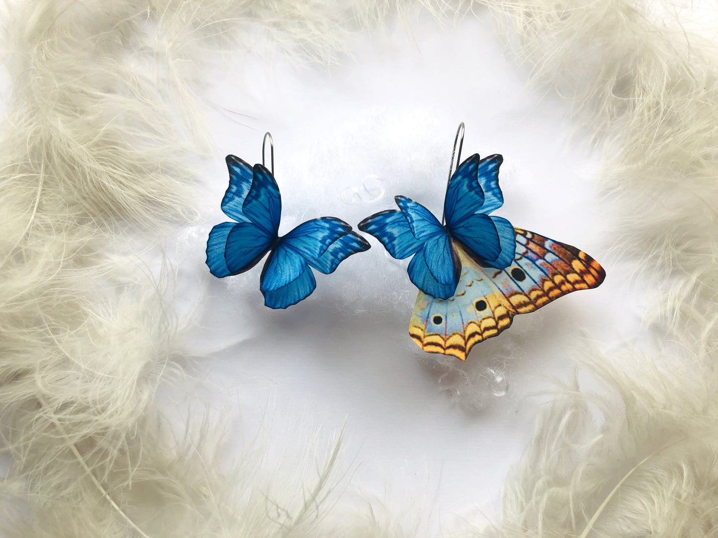 Royal Blue Butterfly Earrings on a white feathers background