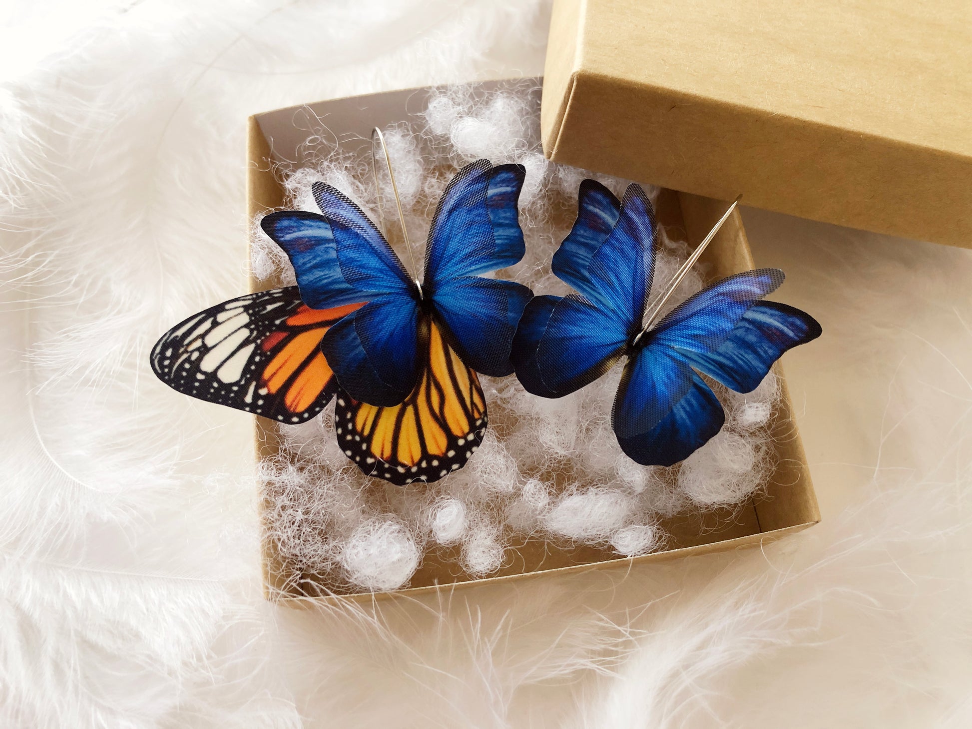 Korean-style earrings featuring vibrant blue butterfly wings and floral designs