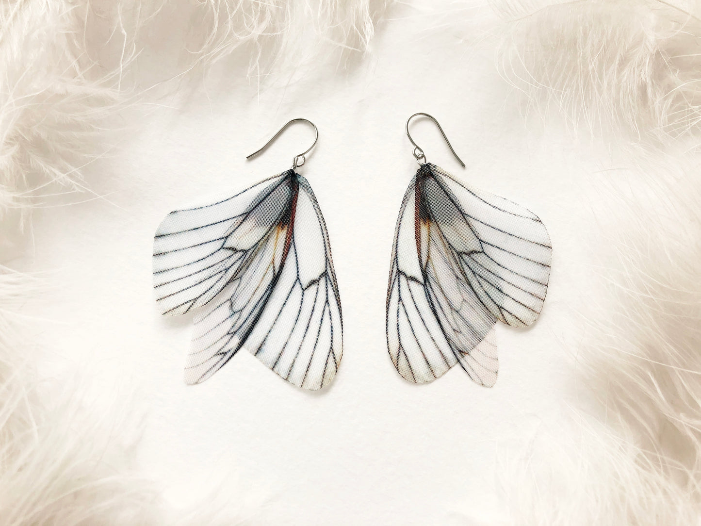 White angel wing earrings on a white background