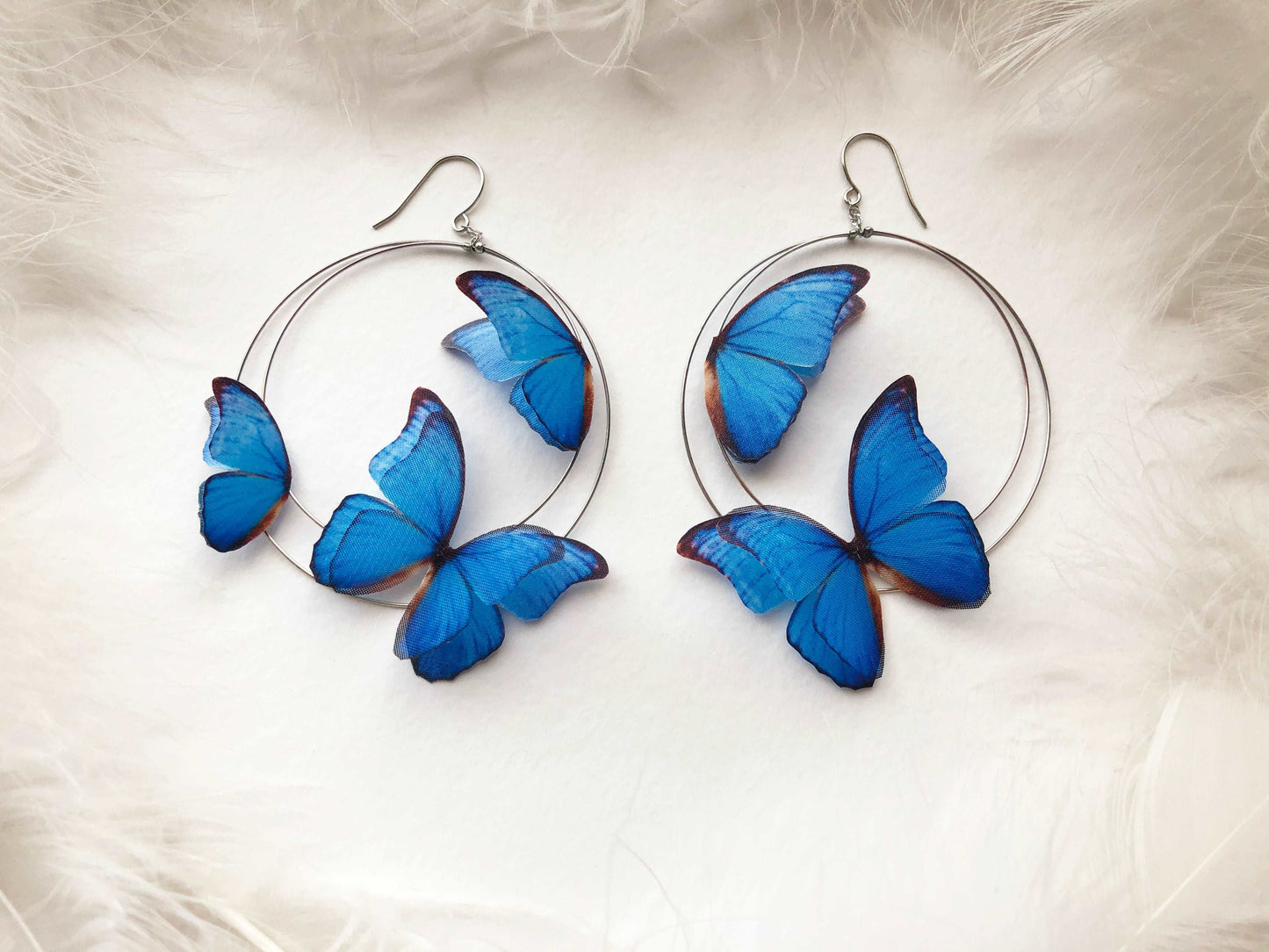 Hoop Earrings with Blue Butterflies on White Feathers Background