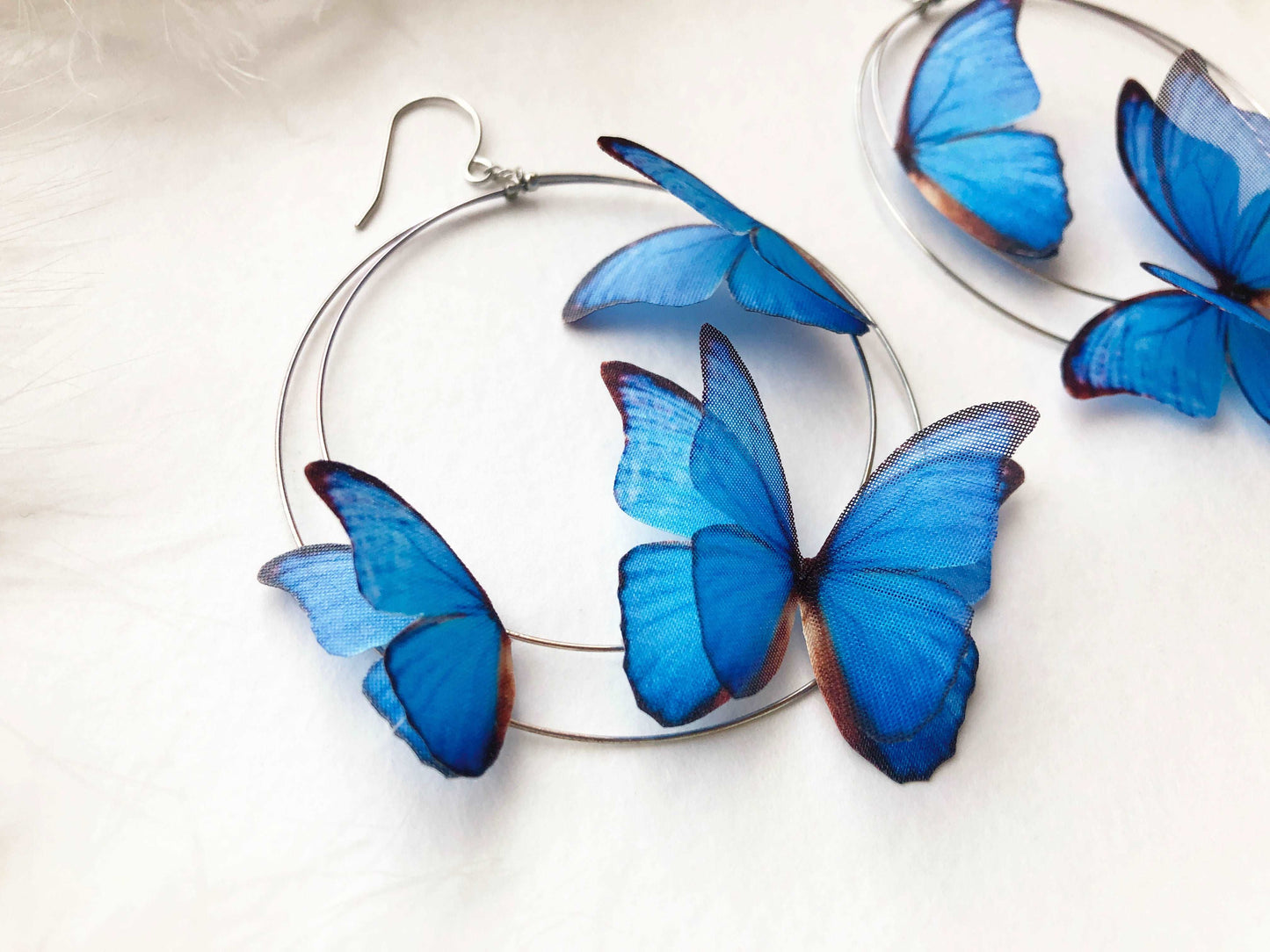 Hoop Earrings with 3D Blue Butterflies on White Feathers Background