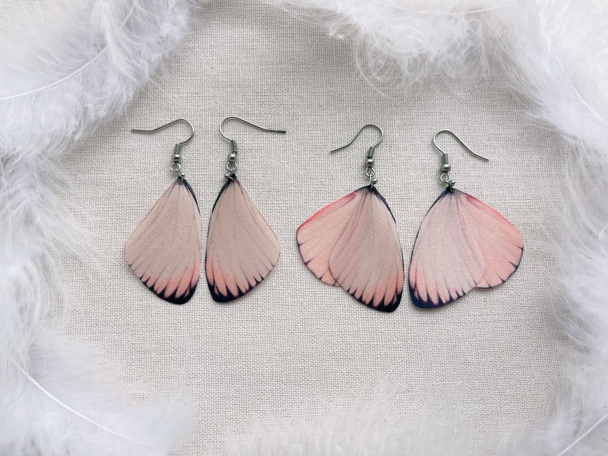 2 Pairs of Butterfly Earrings on White Feathers Background
