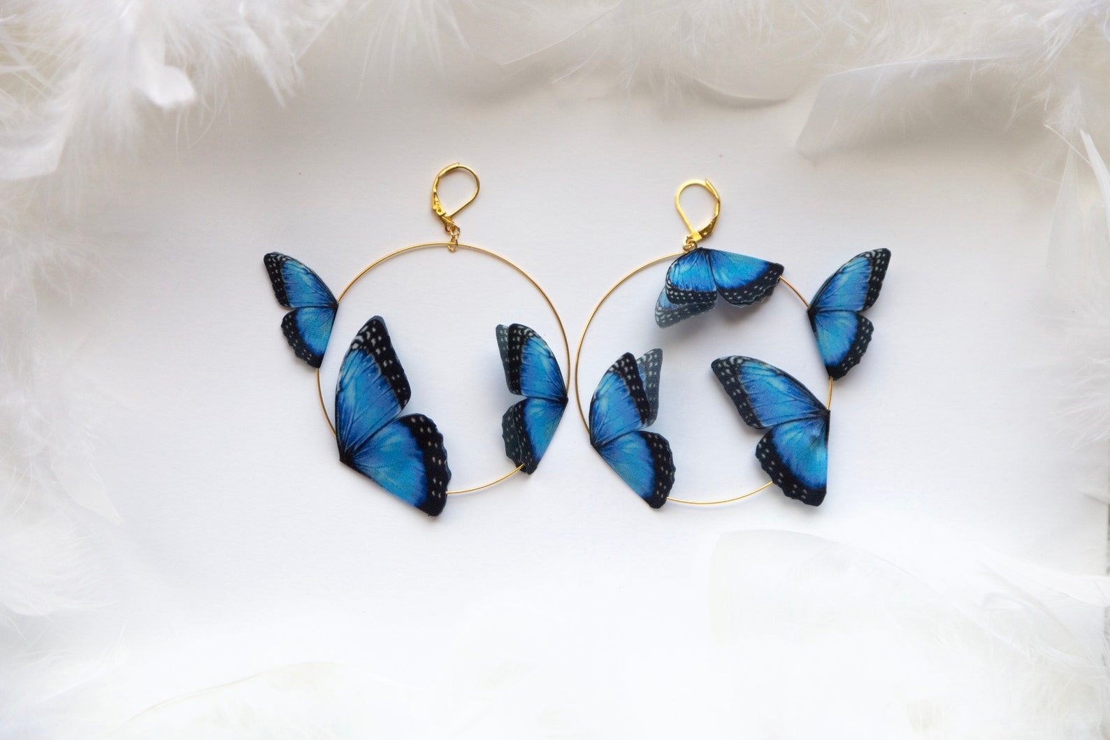 Close-up of sapphire blue butterfly charm on thin gold hoop earring