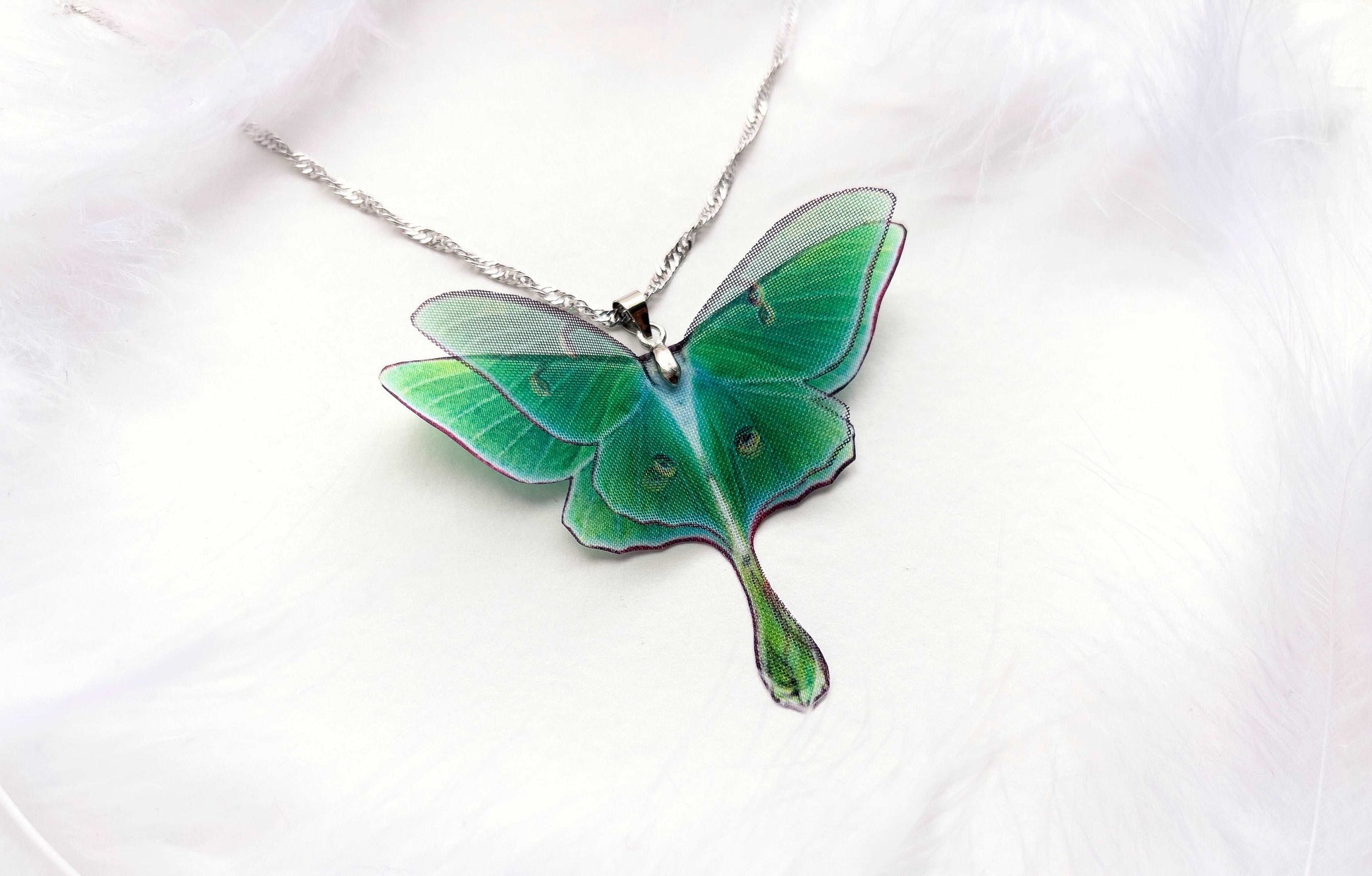 Green Lunar Moth Pendant with chain on a nature-inspired background - Show off your love for the environment with this eco-friendly jewelry piece
