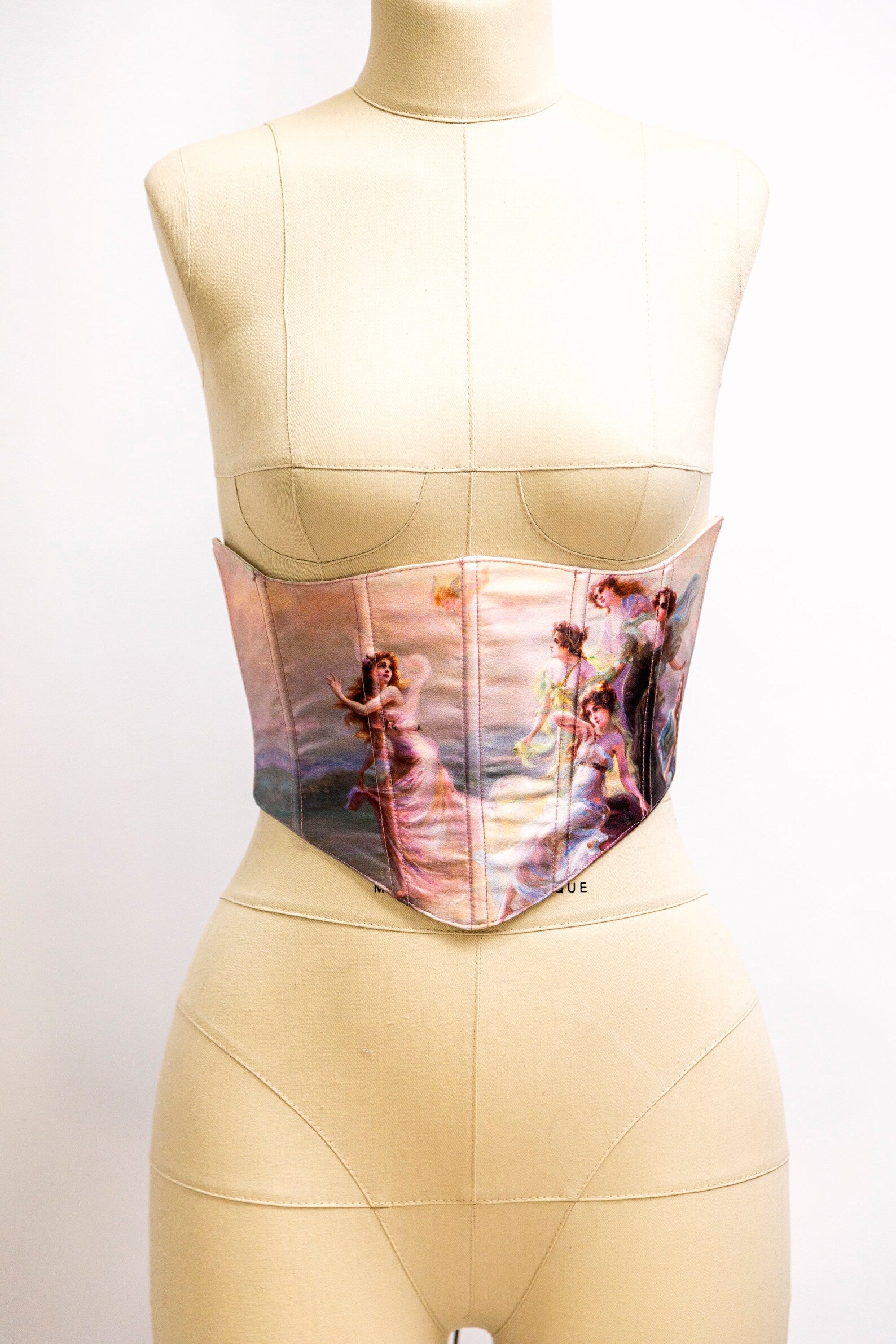 A side view of a pink satin underbust corset with silver hardware and lacing